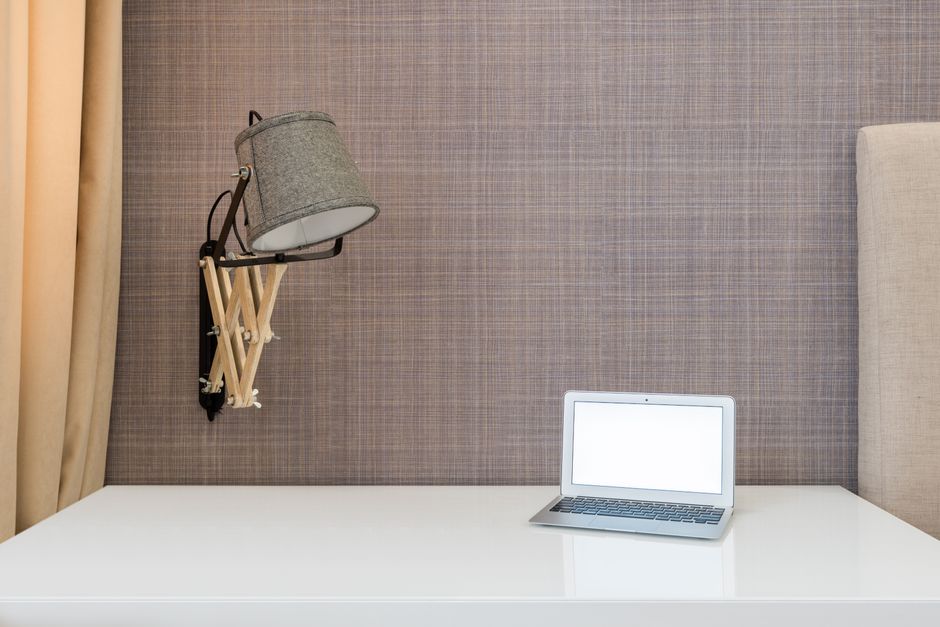 Clean, modern desk setup featuring a laptop, blueprints, and a miniature architectural model of a house, symbolizing real ...