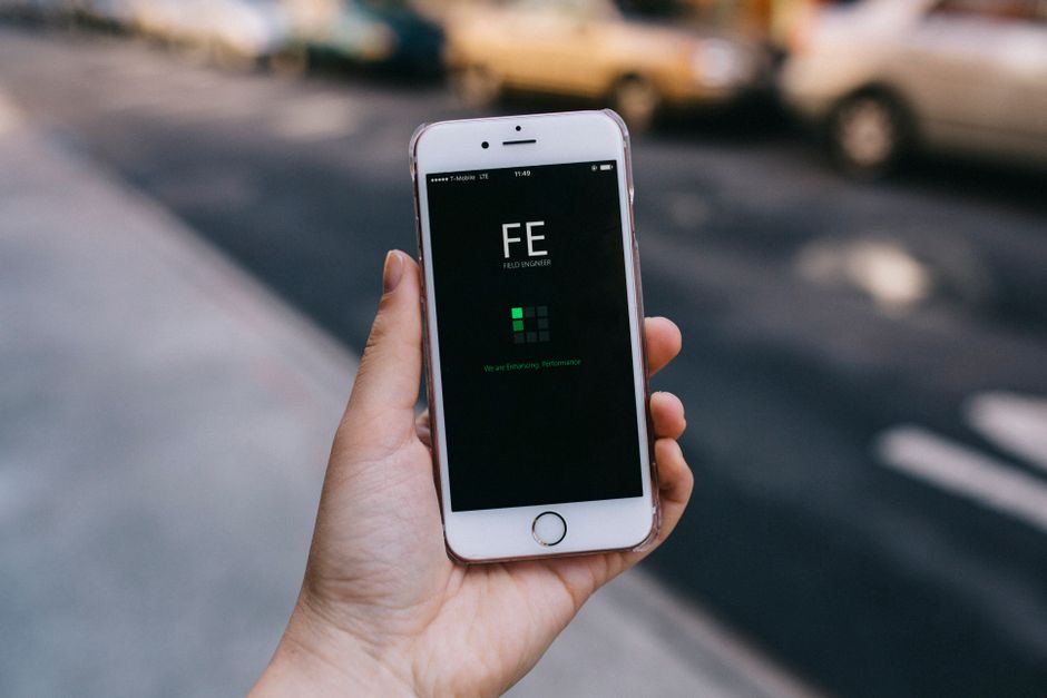 A close-up of a person's hands holding a smartphone displaying a modern real estate application, with property listings visible on the screen.